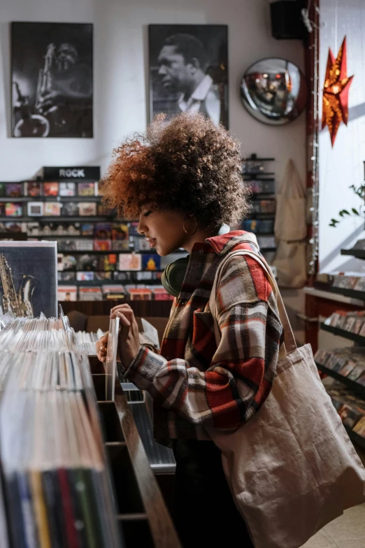 a woman looking at records in a record store, trending on pexels, curly afro, seasonal, slightly pixelated, holding a gold bag