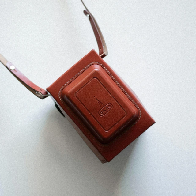 a brown case sitting on top of a white table, red camera, eva elfie, fez video game, photography ultrafine detail