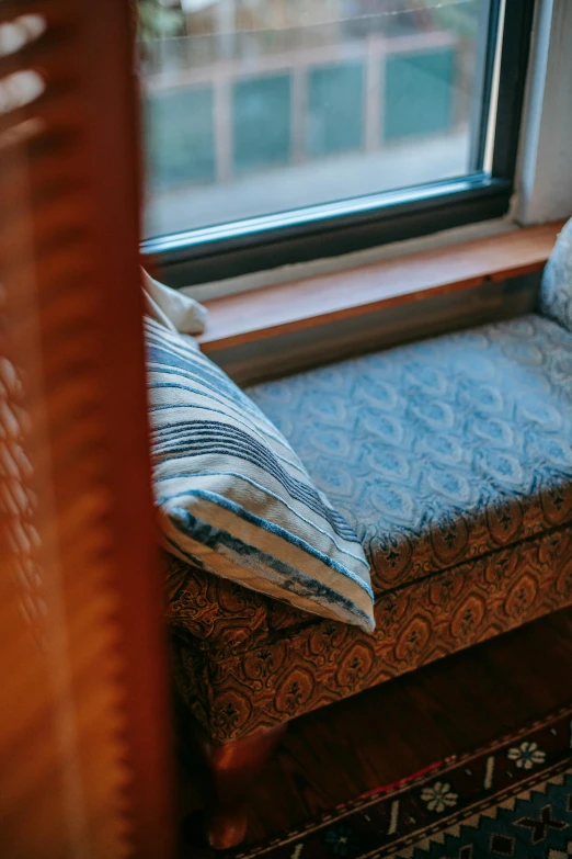 a cat sitting on a window seat in front of a window, unsplash, arts and crafts movement, old couch, patterned clothing, high angle close up shot, picture of a loft in morning