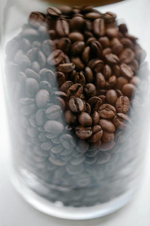 a glass jar filled with coffee beans on top of a table, thumbnail, ballard, up-close, product shot