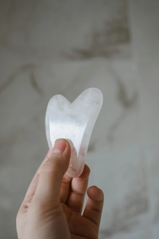 a person holding a piece of tissue in their hand, a marble sculpture, by Jessie Algie, trending on pexels, hurufiyya, heart-shaped face, made of crystal, soft pads, semi-transparent