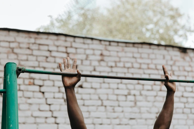 a man hanging on a metal bar in front of a brick wall, by Emma Andijewska, pexels contest winner, happening, hands reaching for her, local gym, background image, photo of a black woman