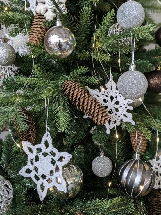 a close up of a christmas tree with ornaments, grey and silver, snowflakes, woodland, medium close shot