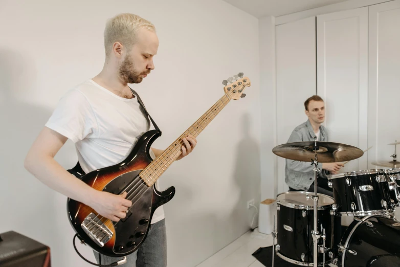 a man that is playing a guitar in a room, in a white room, greg rutkowski and jakub rebelka, profile image, drums