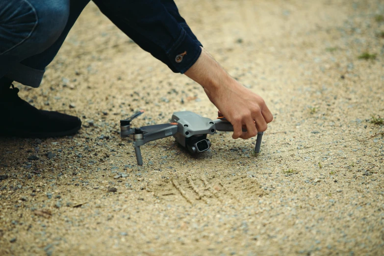 a man holding a remote control device on a dirt road, pexels contest winner, plein air, police drones, on the sand, crawling, birds are all over the ground