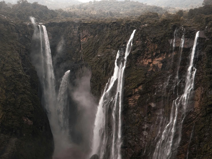 a group of people standing in front of a waterfall, pexels contest winner, romanticism, “ aerial view of a mountain, grey mist, multiple waterfalls, chriss foss