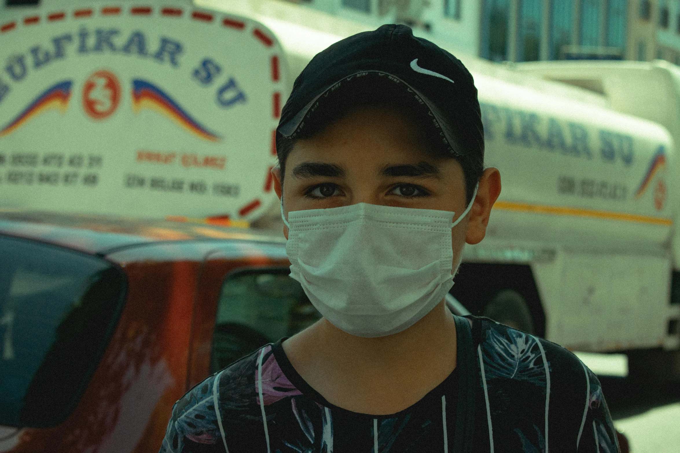 a boy wearing a face mask standing in front of a truck, pexels, hyperrealism, low quality footage, turkey, hospital, worksafe. instagram photo