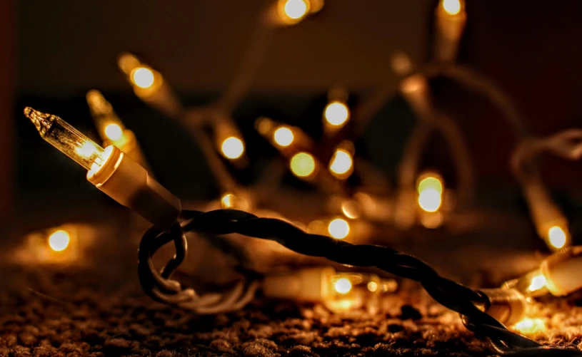 a close up of a string of lights, by Matija Jama, pexels, holiday season, vanilla - colored lighting, light casting onto the ground, instagram post