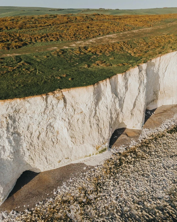 a man riding a surfboard on top of a white cliff, an album cover, pexels contest winner, soil landscape, the thames is dry, landslide road, farming