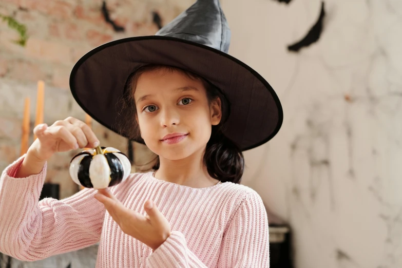 a little girl in a witch hat holding a pumpkin, by Helen Stevenson, pixabay, a woman holding an orb, modelling clay, dafne keen, 15081959 21121991 01012000 4k