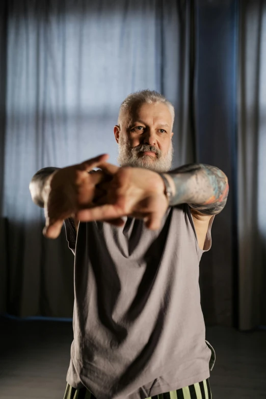 a man holding a baseball bat in a room, a tattoo, inspired by Lajos Vajda, unsplash, symbolism, silver hair and beard, pointing at the camera, yoga, hand gesture