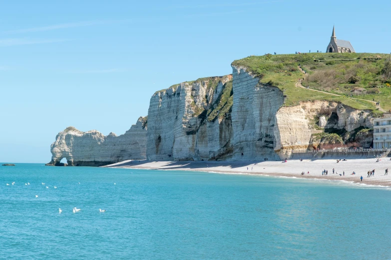 a group of people standing on top of a beach next to the ocean, les nabis, chalk cliffs above, french features, clear blue skies, avalon