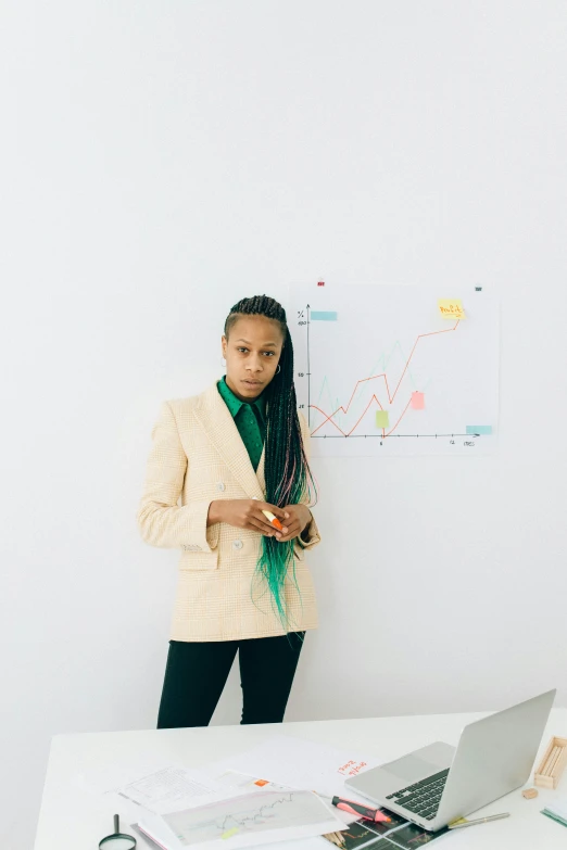 a woman standing in front of a laptop computer, trending on unsplash, analytical art, wearing a colorful men's suit, teaching, with a ponytail, androgynous person
