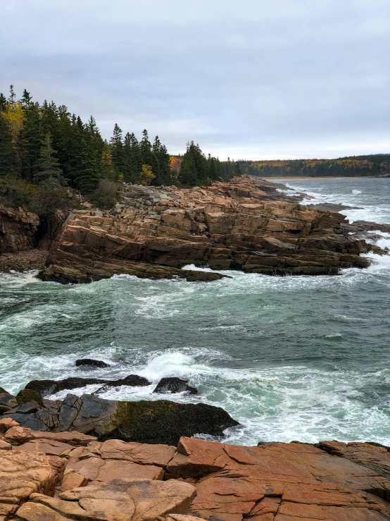 a man standing on top of a rocky cliff next to the ocean, a picture, inspired by Winslow Homer, pexels contest winner, rapids, mid fall, slide show, full frame image