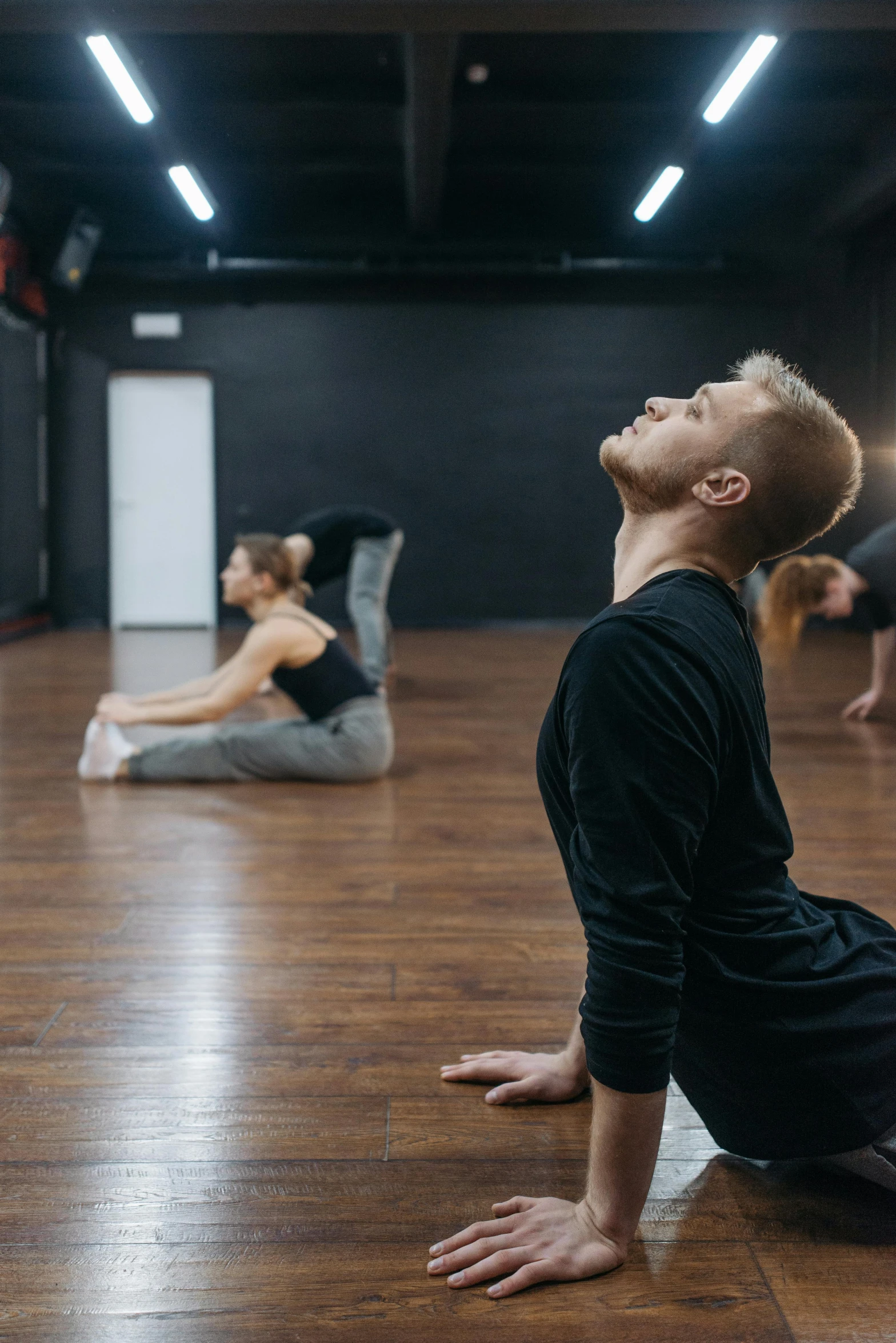 a group of people doing yoga in a room, by James Morris, trending on pexels, arabesque, classic dancer striking a pose, looking to his left, lachlan bailey, half turned around