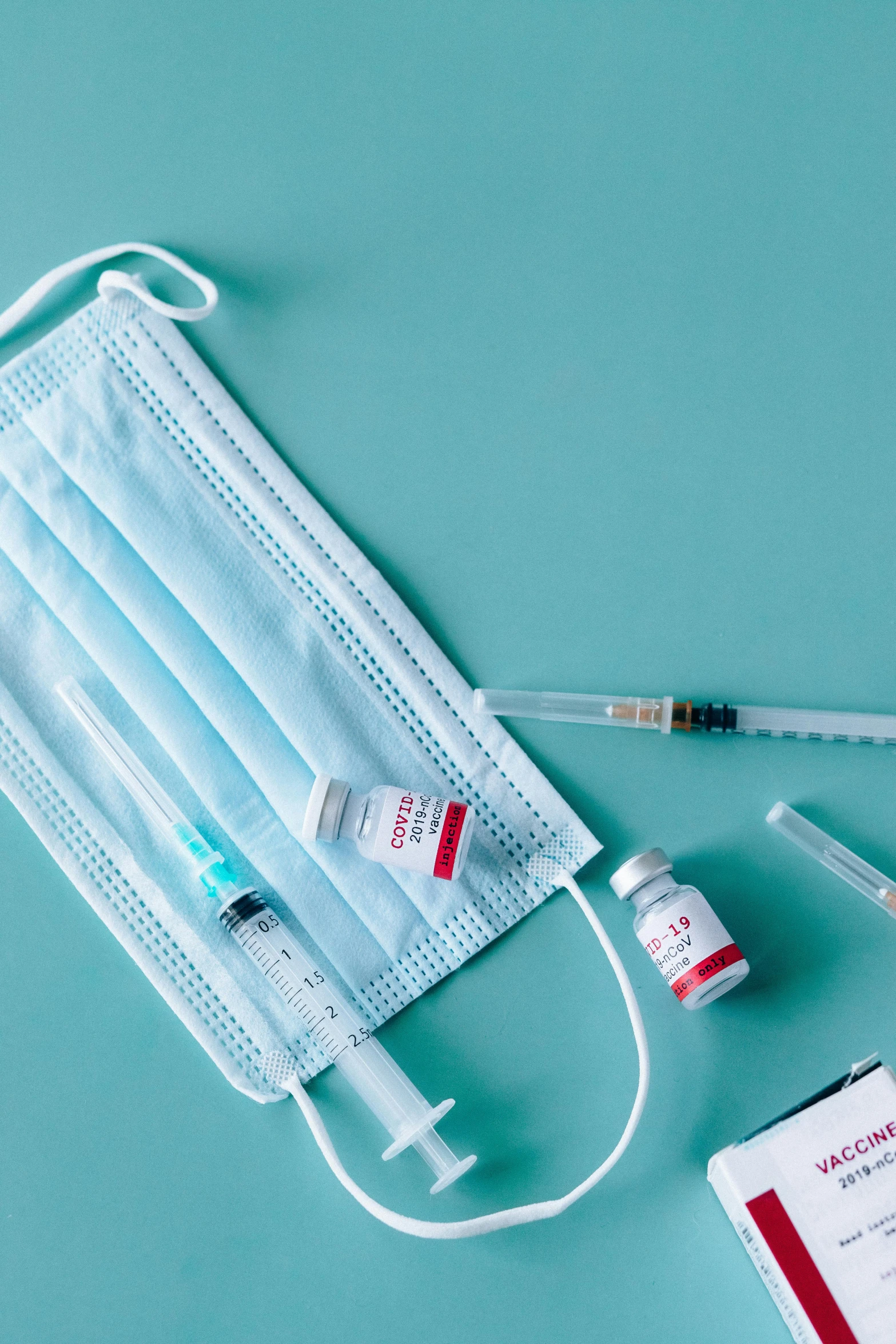 a medical kit sitting on top of a blue surface, masks, holding syringe, white and teal metallic accents, thumbnail