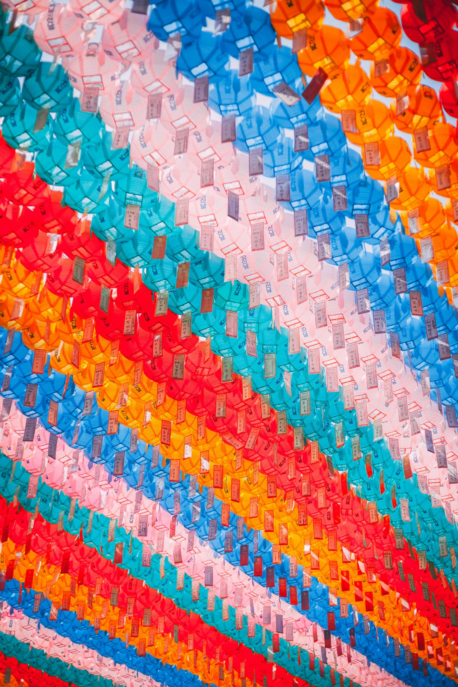 a multicolored blanket sitting on top of a bed, inspired by Kubisi art, unsplash, kinetic art, plastic bottles, shot from below, vietnam, made of lollypops