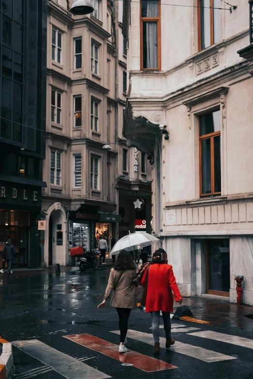 a couple of people walking across a street with an umbrella, a photo, by Niyazi Selimoglu, pexels contest winner, art nouveau, wearing red jacket, gif, buildings carved out of stone, presents