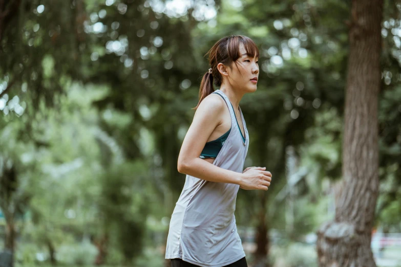 a woman running in a park with trees in the background, pexels contest winner, renaissance, wearing : tanktop, young asian woman, profile image, thumbnail