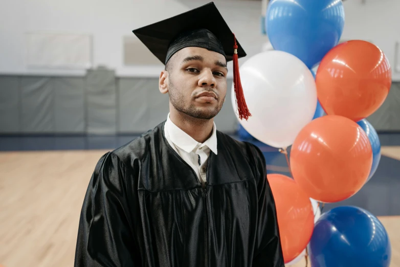 a man standing in front of a bunch of balloons, a portrait, unsplash, academic art, wearing an academic gown, xxxtentacion, close up portrait photo, eric parker