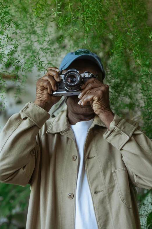 a man taking a picture with a camera, inspired by Gordon Parks, tyler the creator, looking old, 2019 trending photo, lush surroundings