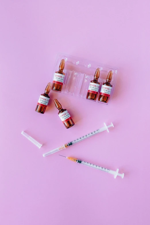 three vials and a syet on a pink background, by Julia Pishtar, pexels contest winner, antipodeans, syringe, flatlay, teenage girl, 4 0 0 0 samples