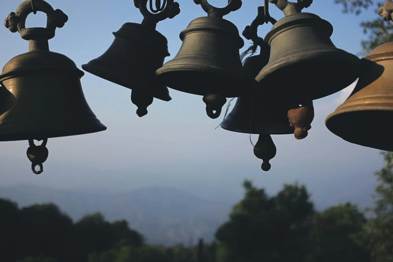 a bunch of bells hanging from a wire, by Carey Morris, pexels contest winner, baroque, hills in the background, shrines, hazy, instagram post