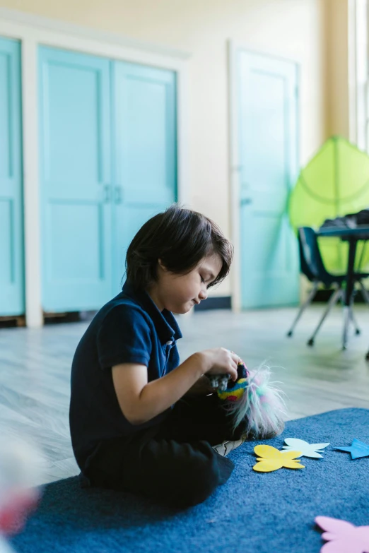 a little boy that is sitting on the floor, pexels contest winner, american barbizon school, cafe for felted animals, blue spiky hair, in a classroom, mission arts environment