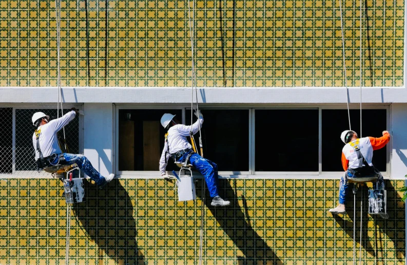 a group of men hanging from the side of a building, a photorealistic painting, pexels contest winner, modernism, patterned tilework, working hard, the madness of mono-yellow, professional paint job