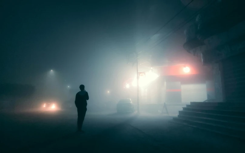 a person standing in the middle of a street at night, a matte painting, unsplash contest winner, conceptual art, cyan fog, mikko lagerstedt, todd hido, by emmanuel lubezki