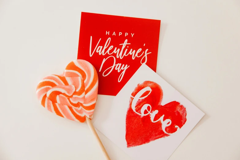 a couple of lollipops sitting next to a valentine's day card, a picture, pexels, background image, instagram picture, product shot, up close picture