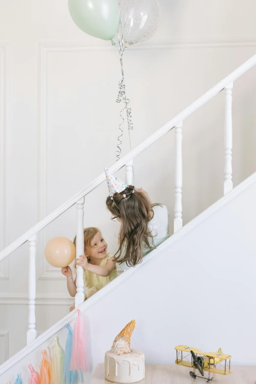 a little girl holding a bunch of balloons, by Alice Mason, pexels contest winner, staircase, silver accessories, two girls, party hats