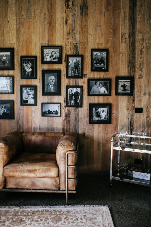 a brown leather chair sitting in front of a wooden wall, photos of family on wall, inside a bar, lounge room, legends