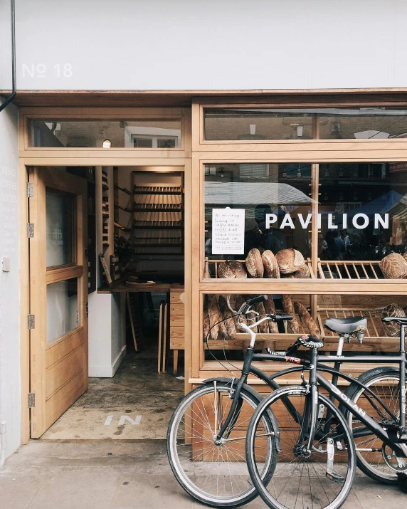 a couple of bikes parked in front of a store, by Maggie Hamilton, trending on unsplash, pavilion, holding a baguette, saloon exterior, 🚿🗝📝