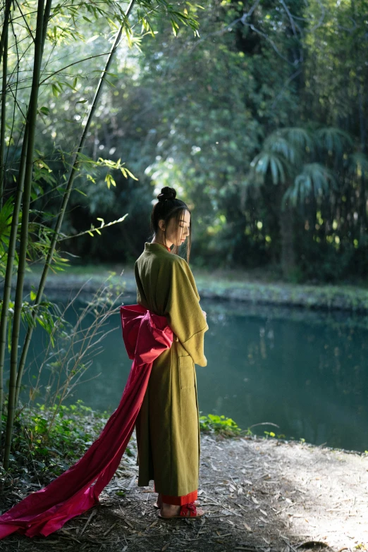 a woman standing in front of a body of water, inspired by Cui Bai, green robes, lush surroundings, movie still, [ cinematic