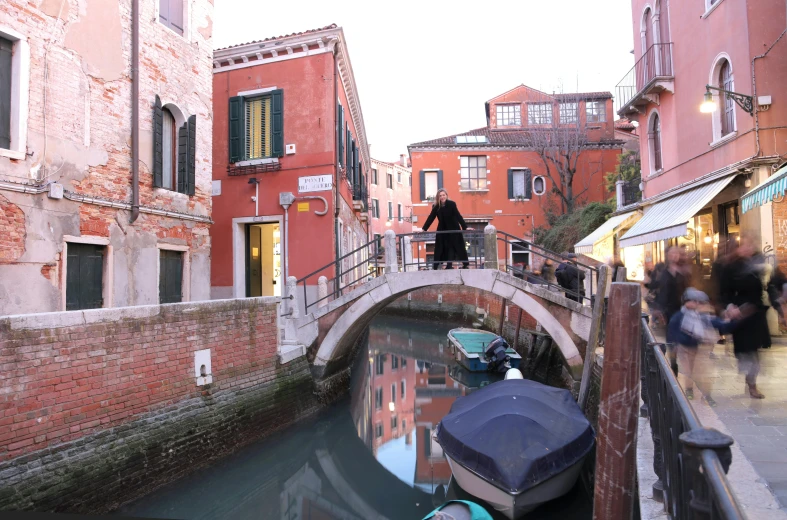 a couple of boats that are in the water, a picture, inspired by Quirizio di Giovanni da Murano, pexels contest winner, standing on a bridge, alley, distant full body view, a woman