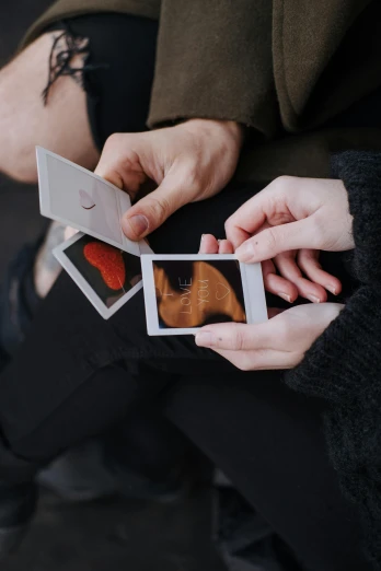 a couple of people that are holding some pictures, by Julia Pishtar, pexels contest winner, happening, fetus, cardistry, contracept, without duplicate image
