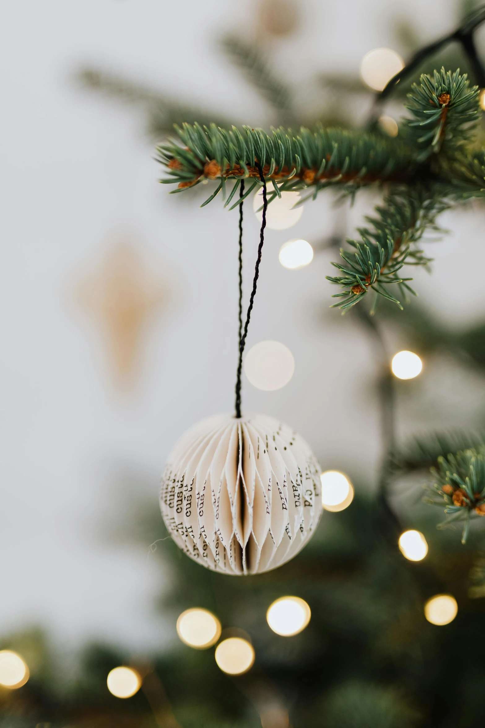 a white ornament hanging from a christmas tree, a photo, pexels, ball shaped accordion sleeve, made of paper, full product shot, back