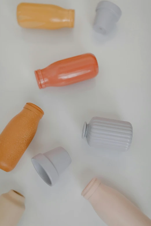 a group of plastic bottles sitting on top of a table, inspired by Giorgio Morandi, trending on unsplash, orange pastel colors, made of clay, detailed product image, detail shot
