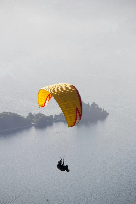 a person parasailing over a body of water, yellow mist, view from the top, - n 9, no cropping