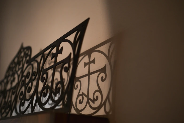 a close up of a metal railing on a wall, inspired by André Kertész, unsplash, arts and crafts movement, shadow of catholic church cross, on the altar, low-light photograph, low-angle