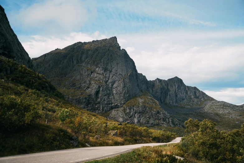 a motorcycle parked on the side of a road next to a mountain, by Roar Kjernstad, unsplash contest winner, hurufiyya, “ iron bark, natural stone road, view from below, thumbnail