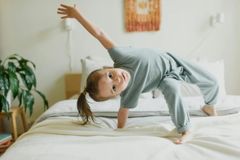 a little girl doing a handstand on a bed, pexels contest winner, wearing a tracksuit, raising an arm, girl running, thumbnail