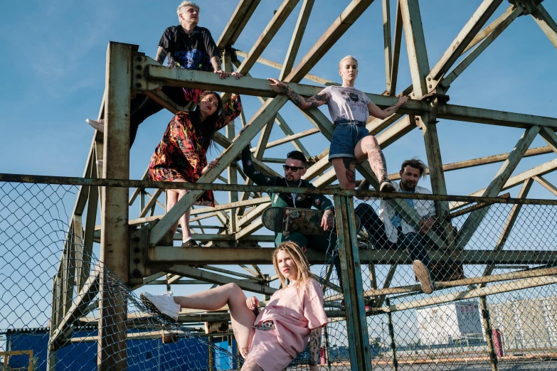 a group of people sitting on top of a metal structure, a portrait, by Lee Loughridge, unsplash, scrapyard, crane shot, with pop punk style, bleached