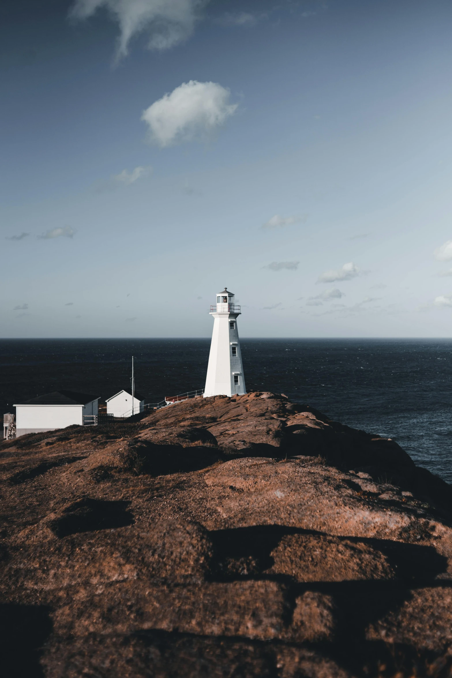 a lighthouse sitting on top of a cliff next to the ocean, ignant, bright white light, looking serious, brown