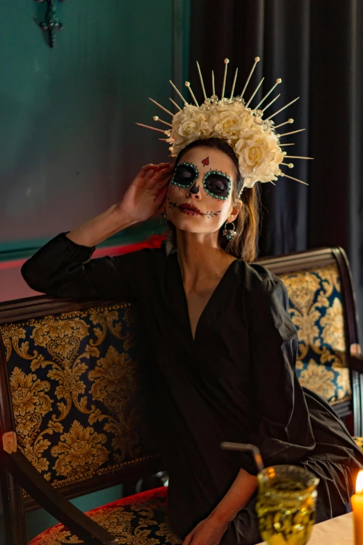 a woman sitting at a table with a mask on, inspired by Hedi Xandt, trending on unsplash, baroque, celebrating day of the dead, sitting in a lounge, crown on head, square