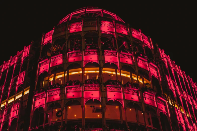 a tall building lit up with pink lights, an album cover, pexels contest winner, berlin secession, detailed glowing red implants, former gasometer in rome, crimson - black beehive, round-cropped