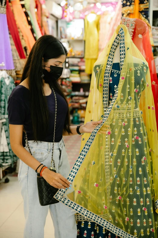 a woman standing next to a mannequin in a store, dressed in a sari, gen z, wearing facemask, finer details : 3