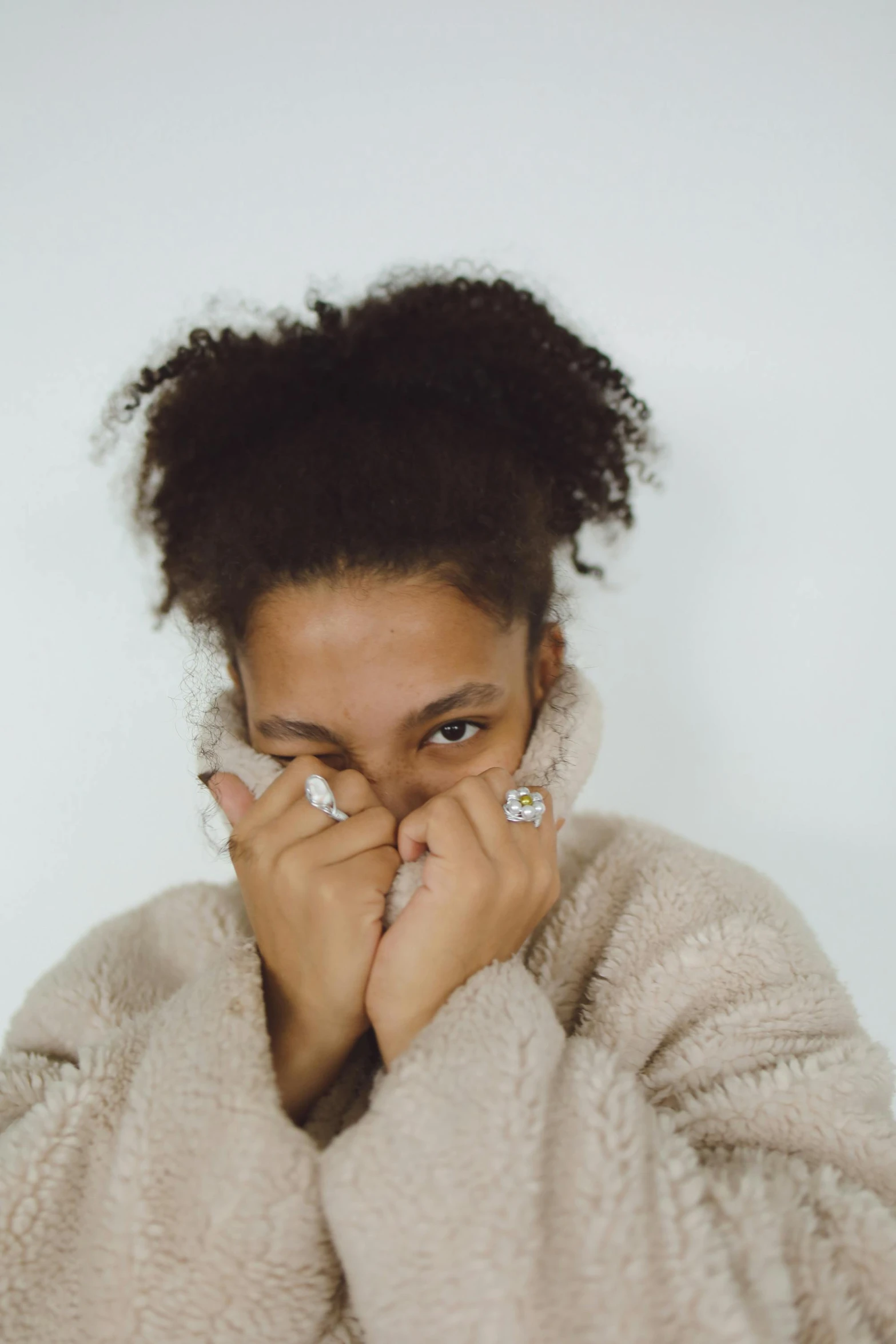 a woman covers her face with a blanket, an album cover, by Dulah Marie Evans, trending on pexels, antipodeans, mixed race woman, wearing two metallic rings, ear floof, wearing an oversized sweater