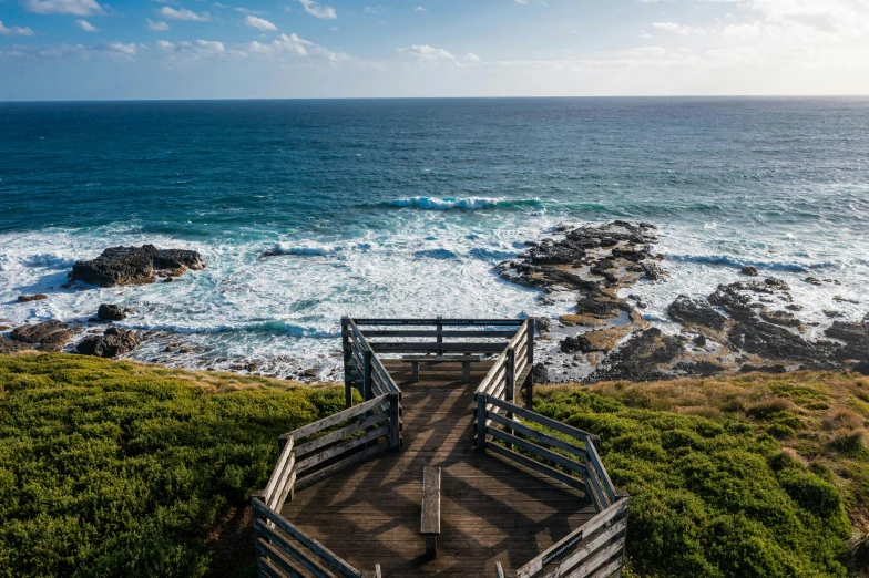 a view of the ocean from the top of a hill, by Peter Churcher, wooden platforms, penrose stairs, rocky beach, set photo